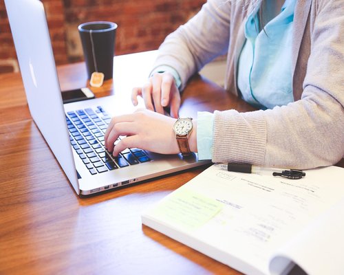 A person typing responsibly on a professional laptop keyboard in an office setup